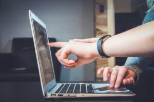 hand pointing to a macbook laptop
