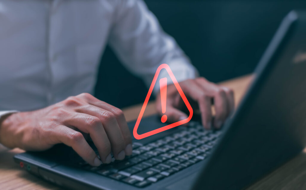 Businessman using computer laptop with triangle caution warning sing for notification error and maintenance concept.